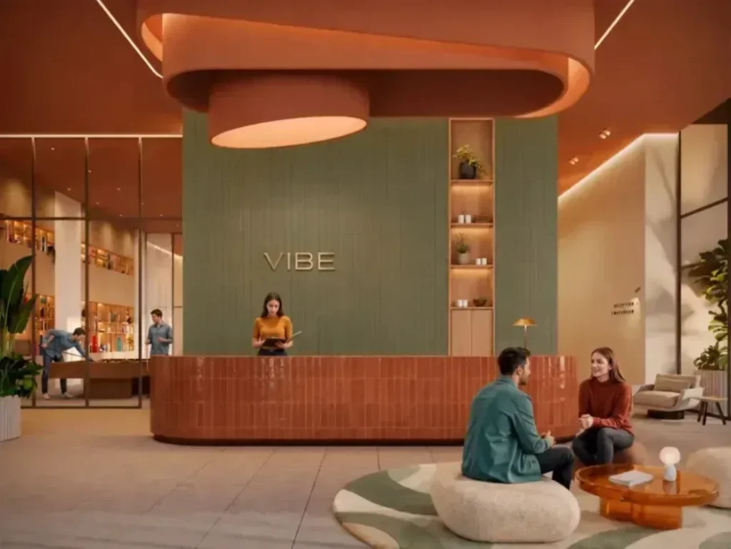 lobby The VIBE reception, with a curved terracotta desk beneath a sculptural swirled ceiling and a green panelled wall carrying the backlit VIBE lettering