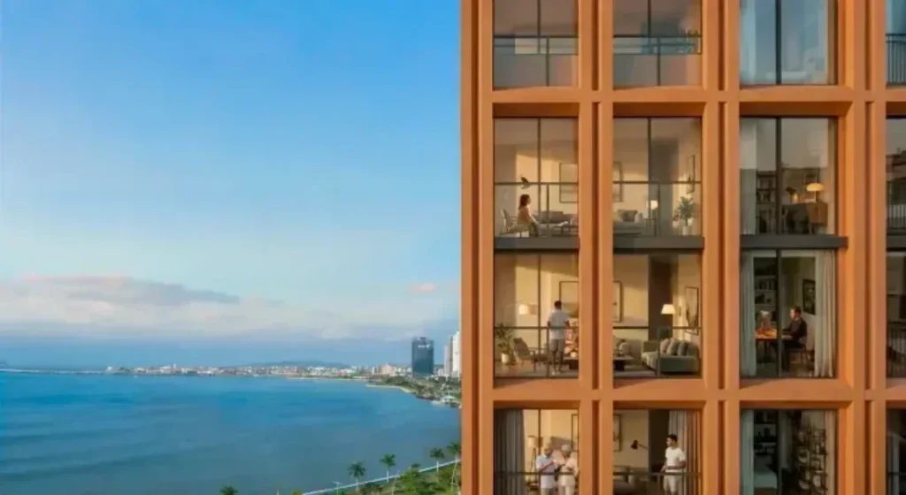 location A corner of the VIBE facade with lit balconies, seen against the open water and distant coastline of Panama Bay